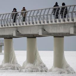 Menschen laufen auf der eingefrorenen Seebrücke in Prerow.