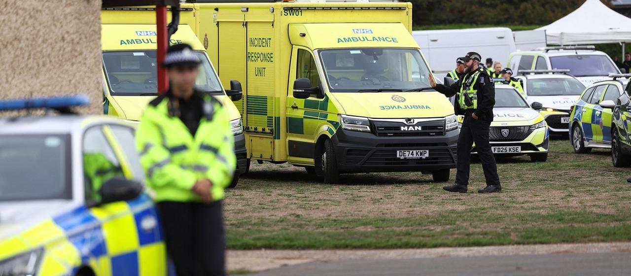 Britische Polizisten befinden sich in der Nähe ihrer Fahrzeuge und Rettungswagen.