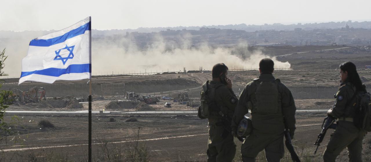 Soldaten stehen neben einer Flagge Israels und beobachten den nördlichen Gazastreifen. 