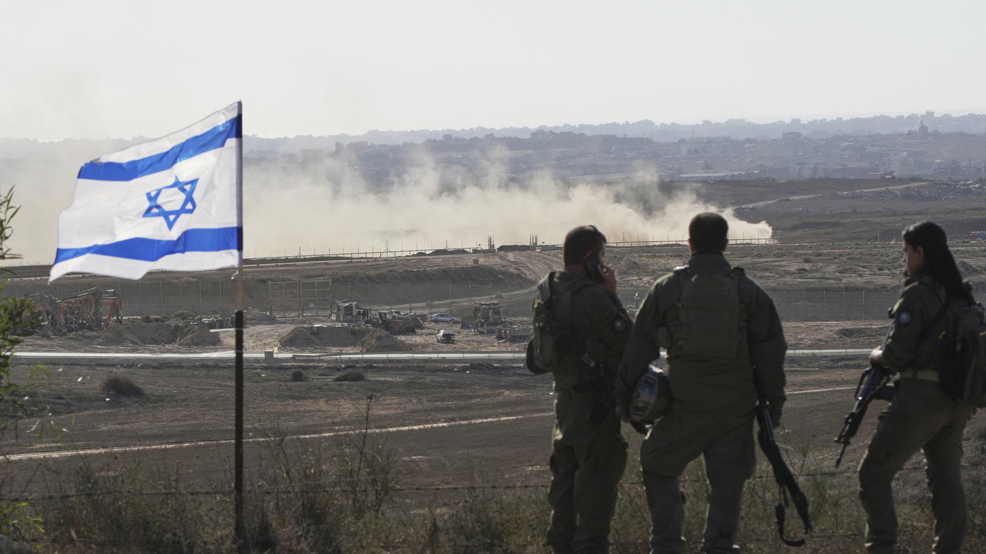 Soldaten stehen neben einer Flagge Israels und beobachten den nördlichen Gazastreifen.  | dpa