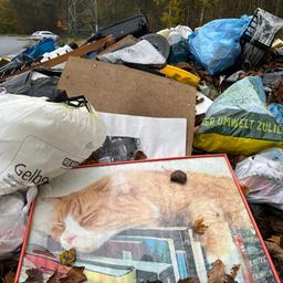 Riesige Haufen von Müll und vollgestopften Plastiktüten liegen auf einem Parkplatz.