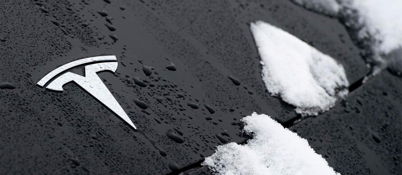 Tesla Logo auf einer schneebedeckten Motorhaube.