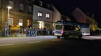Eine Gruppe von Polizeibeamten steht vor einem Ferienhaus in Kröv an der Mosel. Dort lief ein Einsatz wegen des Verdachts der Verwendung verfassungsfeindlicher Parolen.