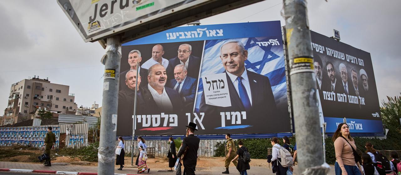 Menschen gehen an einer Wahlplakatwand der Likud-Partei vorbei, auf der Benjamin Netanjahu neben den Vorsitzenden der Oppositionsparteien zu sehen ist