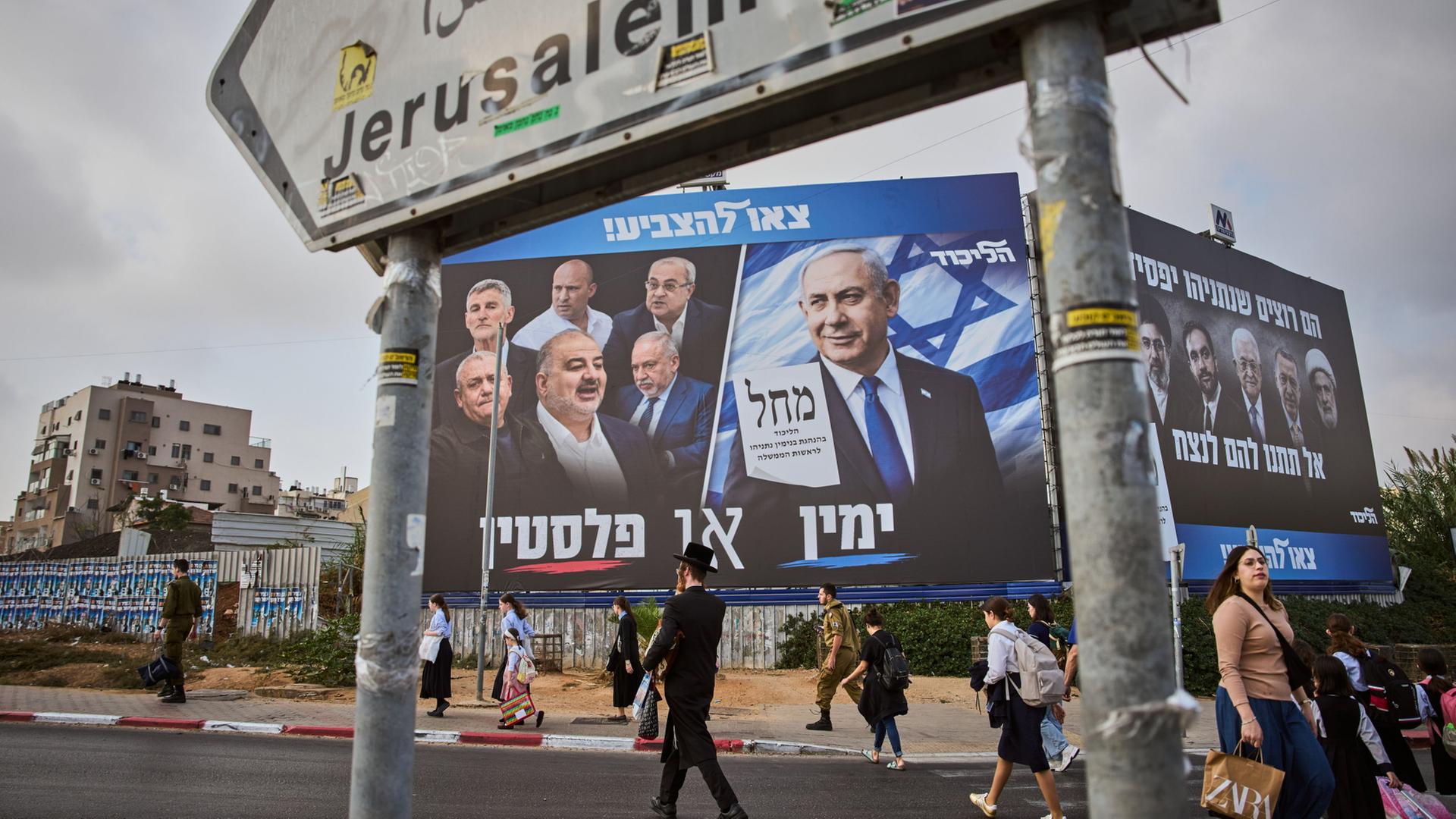Menschen gehen an einer Wahlplakatwand der Likud-Partei vorbei, auf der Benjamin Netanjahu neben den Vorsitzenden der Oppositionsparteien zu sehen ist | AP Photo/Oded Balilty