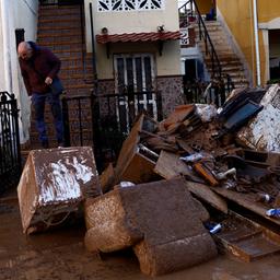 Ein Mann steht vor einem Haus in der spanischen Stadt Utiel. Die Straße ist mit Schlamm und Trümmern übersät.