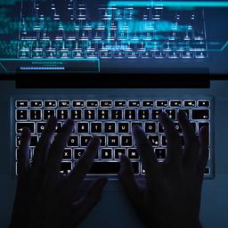 Hände tippen auf einer beleuchteten Tastatur