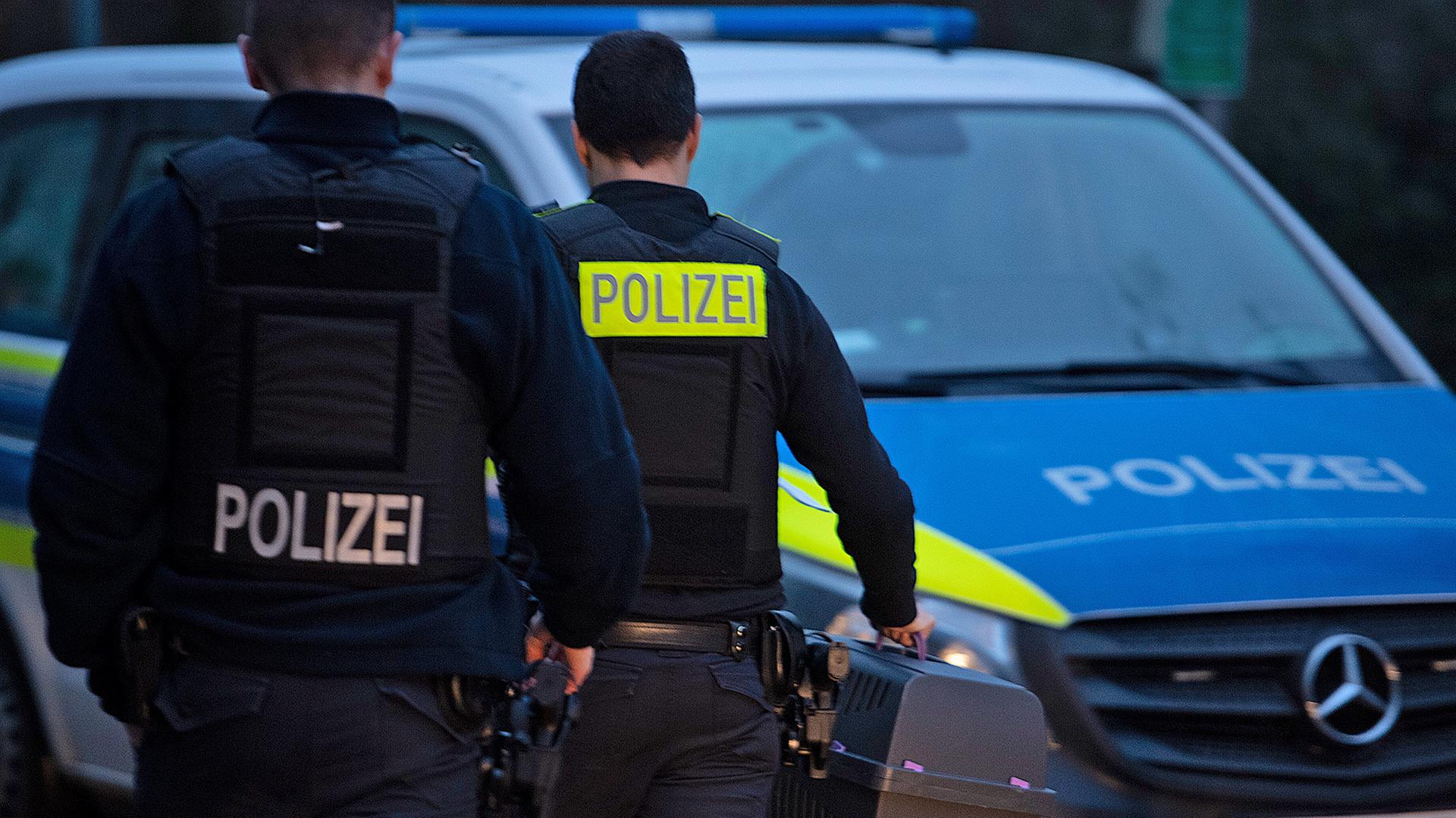 Polizeibeamte gehen in Lichtenberg zu einem Fahrzeug. (Quelle: Picture Alliance/Paul Zinken) | Picture Alliance/Paul Zinken