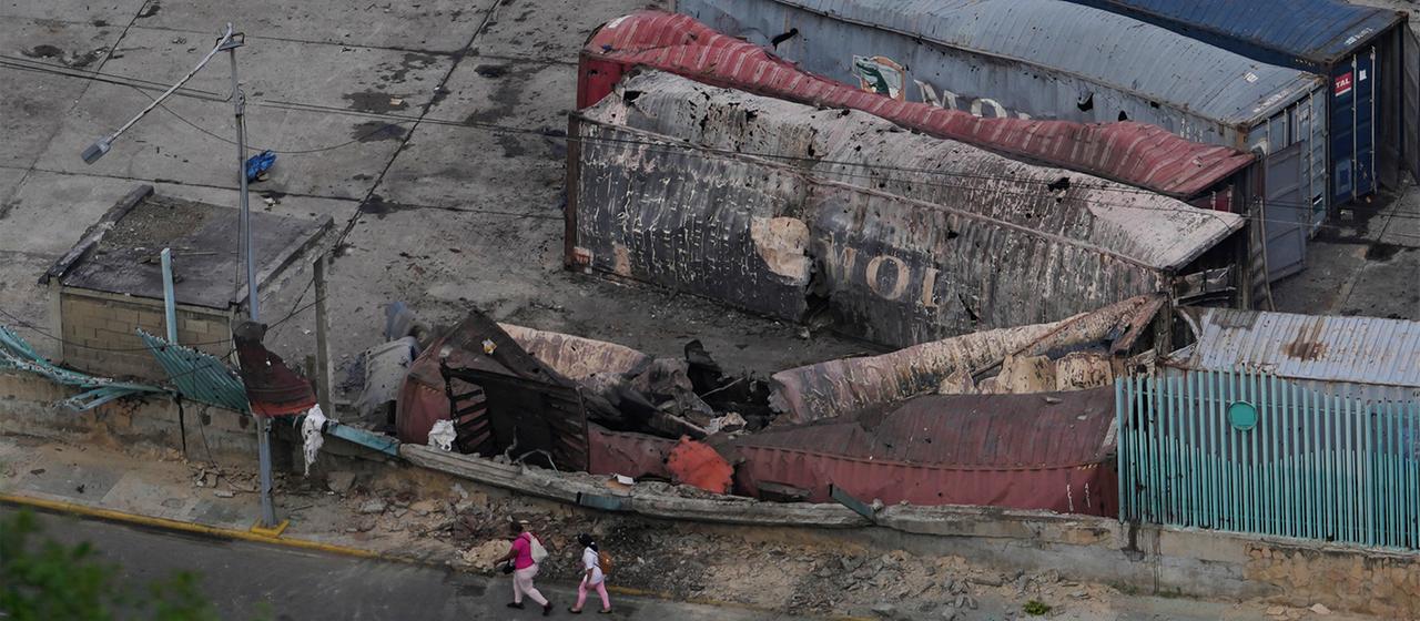 Fußgänger gehen an zerstörten Containern vorbei, die im Hafen von La Guaira liegen.