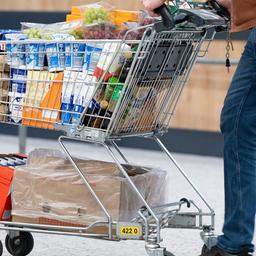 Ein Mann schiebt einen vollen Einkaufswagen mit Lebensmitteln und Getränken.