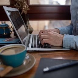 Ein Mann arbeitet in einem Café an einem Laptop.