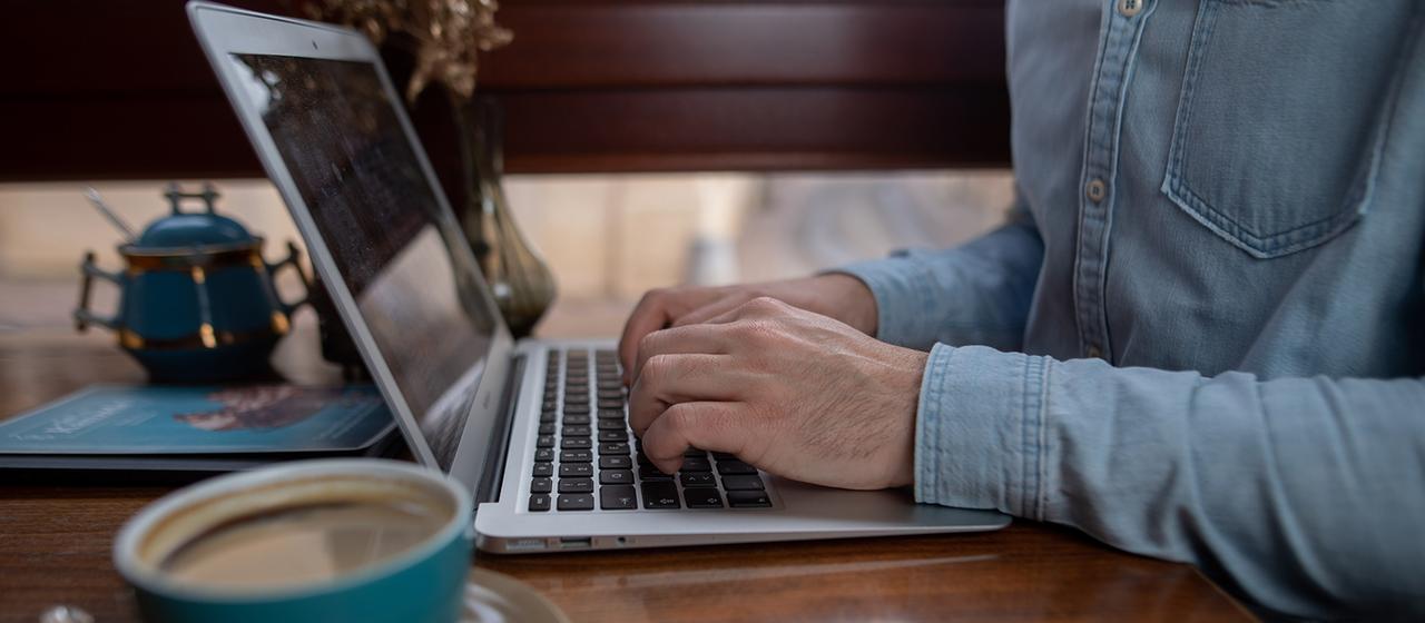 Ein Mann arbeitet in einem Café an einem Laptop.