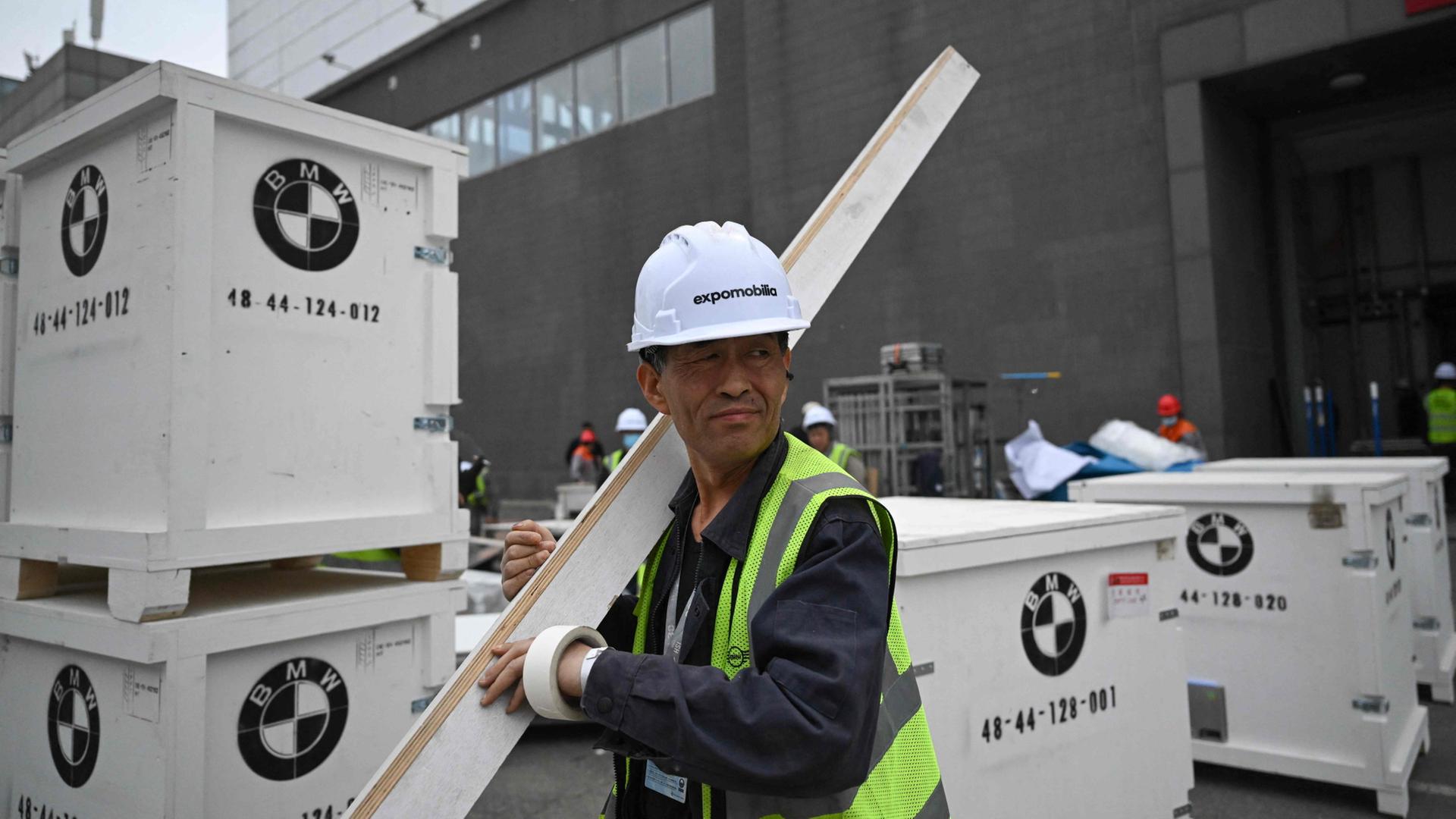 Arbeiter bauen für BMW den Stand bei der Automesse in Peking auf. | AFP