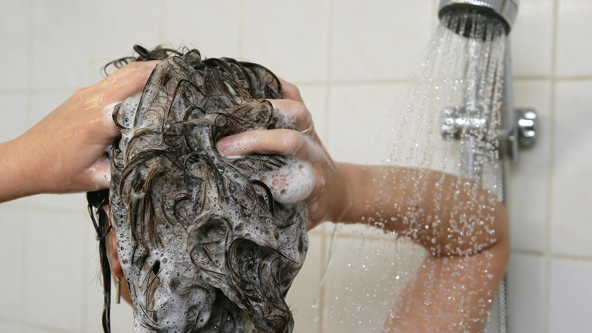 Eine Frau wäscht sich unter der Dusche die Haare. | picture alliance / dpa