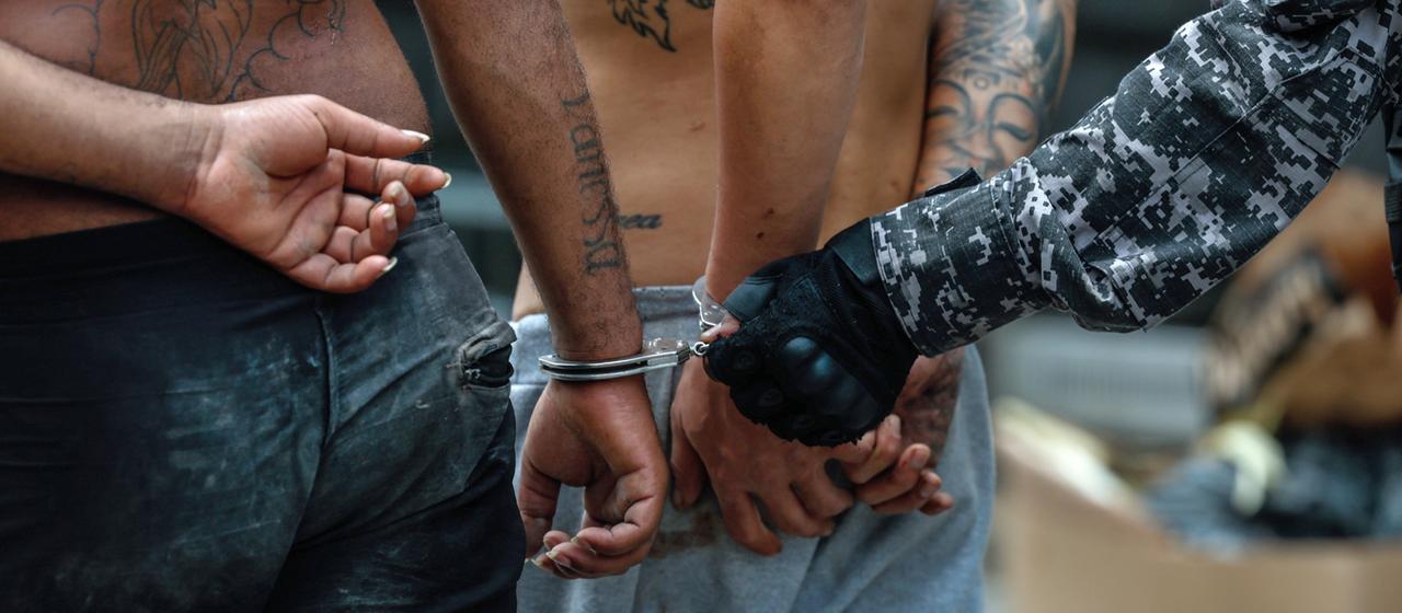 Ein Uniformierter und Menschen in Handschellen in Brasilien.