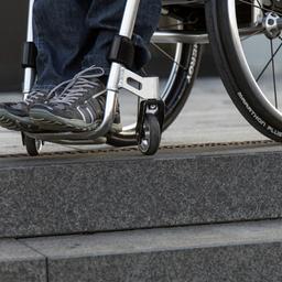 Ein Rollstuhlfahrer steht in seinem Rollstuhl an einer Treppe.