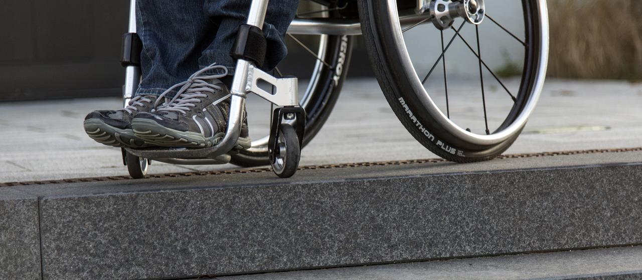Ein Rollstuhlfahrer steht in seinem Rollstuhl an einer Treppe.