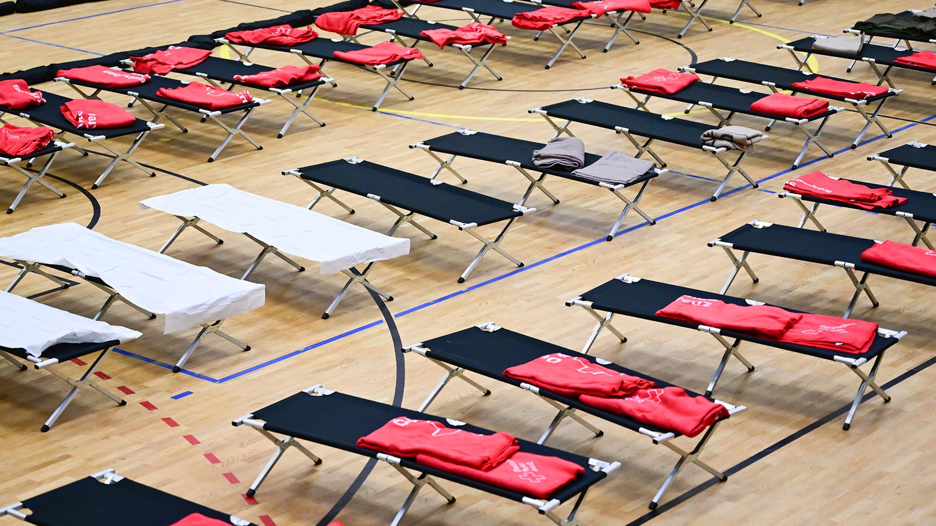 In einer Sporthalle sind zahlreiche Feldbetten aufgestellt. | dpa