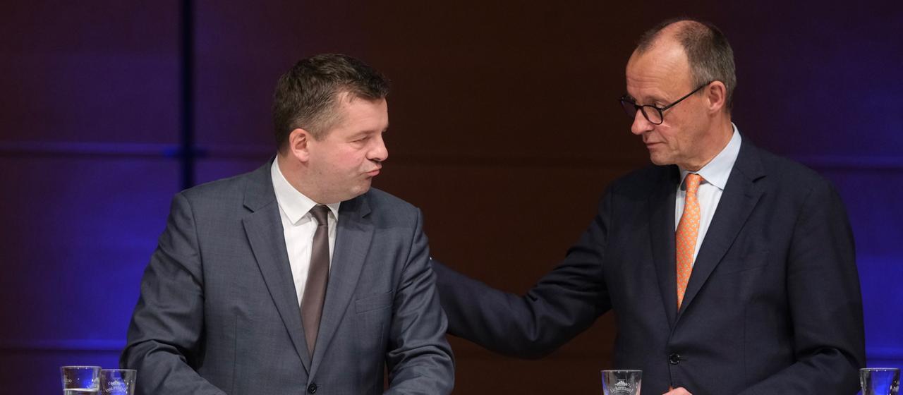 Sven Schulze (l, CDU), Ministerpräsident des Landes Sachsen-Anhalt, und Bundeskanzler Friedrich Merz (CDU) stehen beisammen auf einer Bühne.