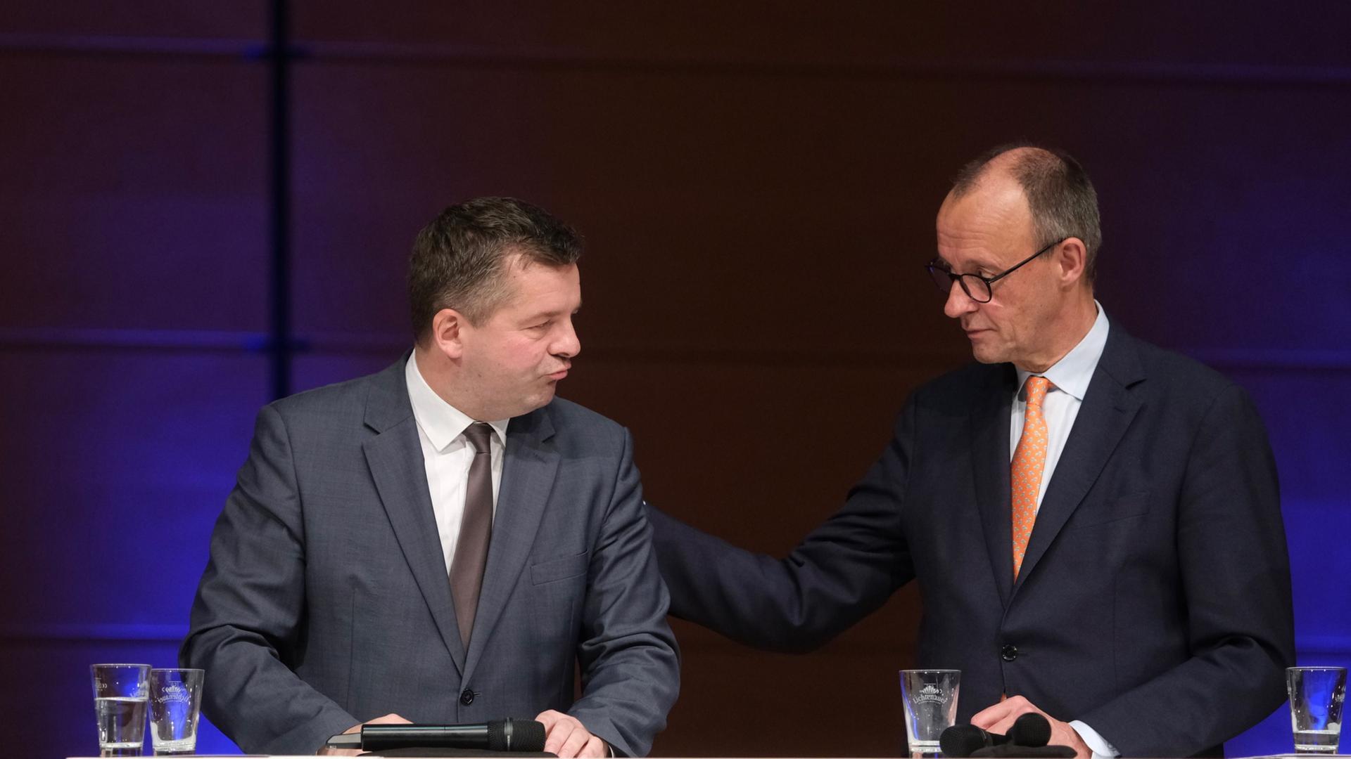 Sven Schulze (l, CDU), Ministerpräsident des Landes Sachsen-Anhalt, und Bundeskanzler Friedrich Merz (CDU) stehen beisammen auf einer Bühne. | Sebastian Willnow/dpa