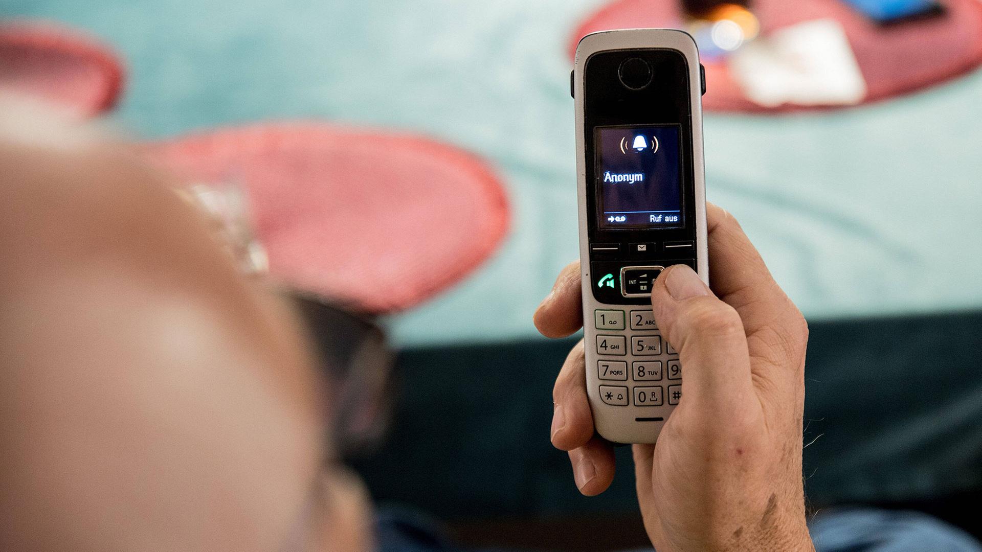 Eine Person, die ein Telefon hält, bei dem ein anonymer Anruf eingeht | IMAGO / Fotostand