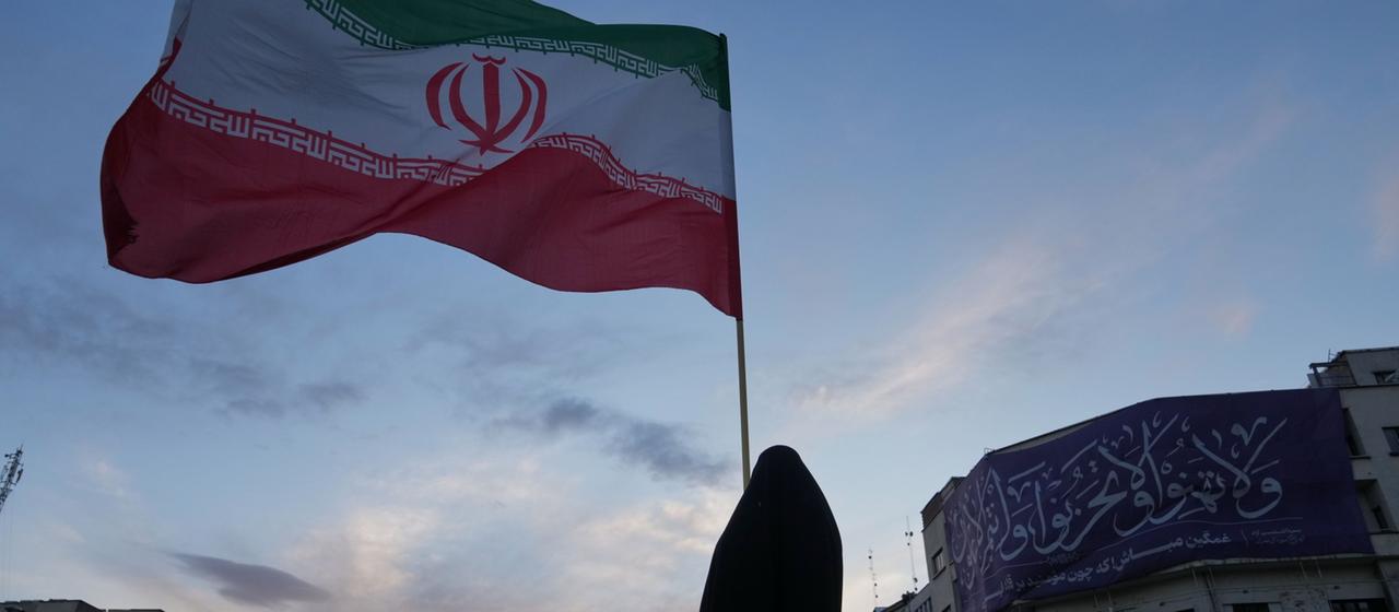 Eine Frau in Teheran hält eine iranische Flagge in die Höhe