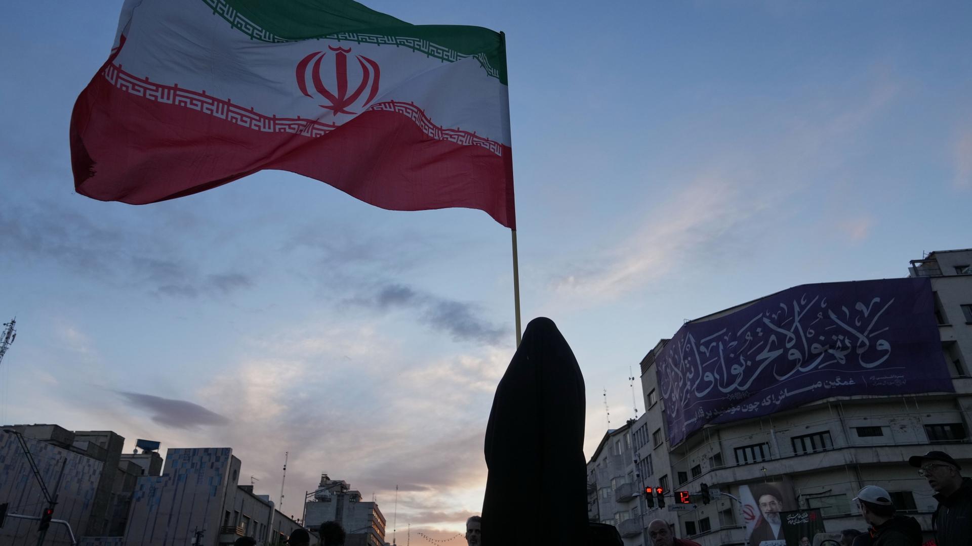 Eine Frau in Teheran hält eine iranische Flagge in die Höhe | AP