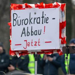 Ein Landwirt hält während der Kundgebung vor dem Brandenburger Tor in Berlin ein Schild mit der Aufschrift "Bürokratie-Abbau! Jetzt" hoch
