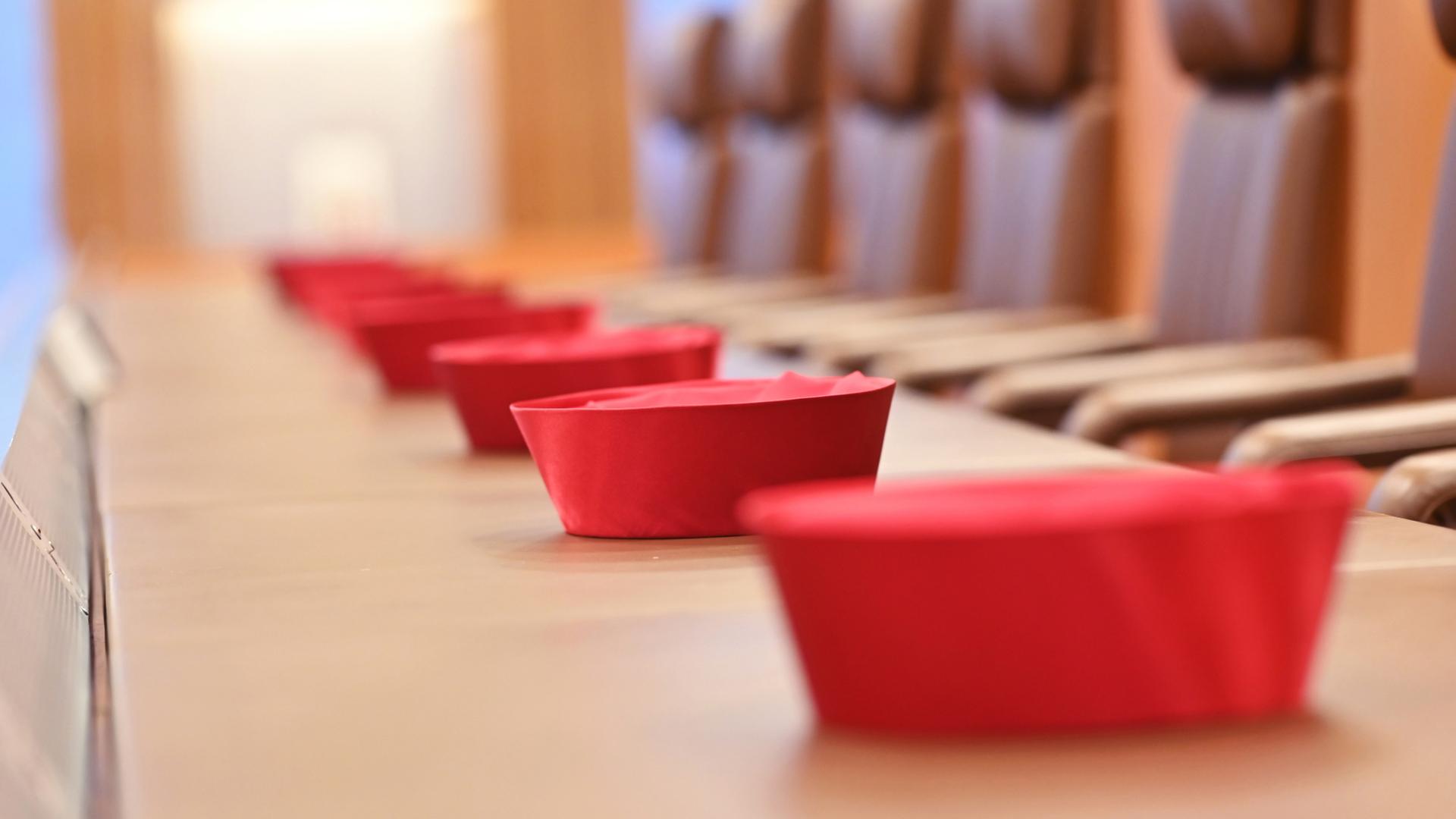 Auf der Richterbank im Sitzungssaal im Bundesverfassungsgericht liegen Barette der Bundesverfassungsrichter des ersten Senats. | dpa