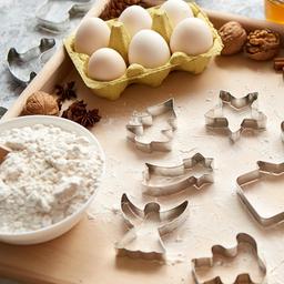 Zutaten und Ausstechformen zum Plätzchen backen auf einem Tisch.