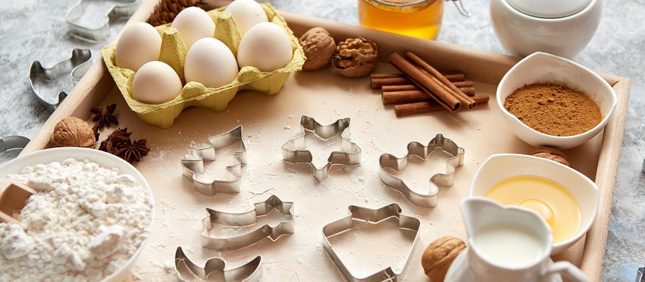 Zutaten und Ausstechformen zum Plätzchen backen auf einem Tisch.