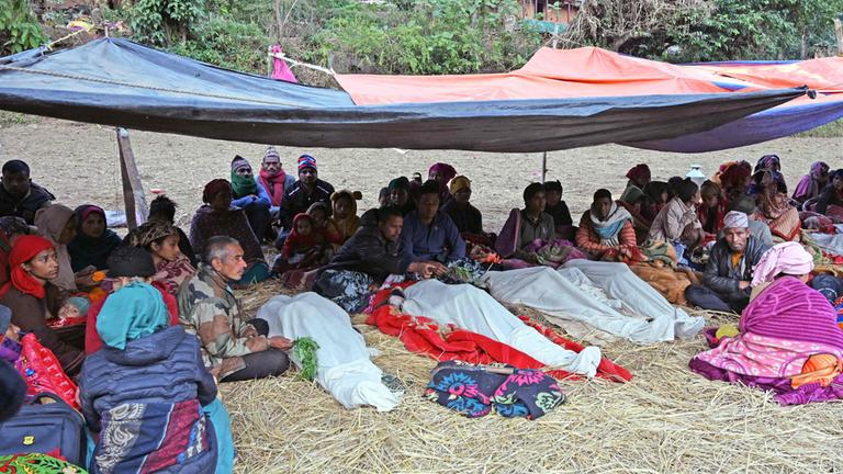 Angehörige sitzen in der Erdbebenregion neben Todesopfern.