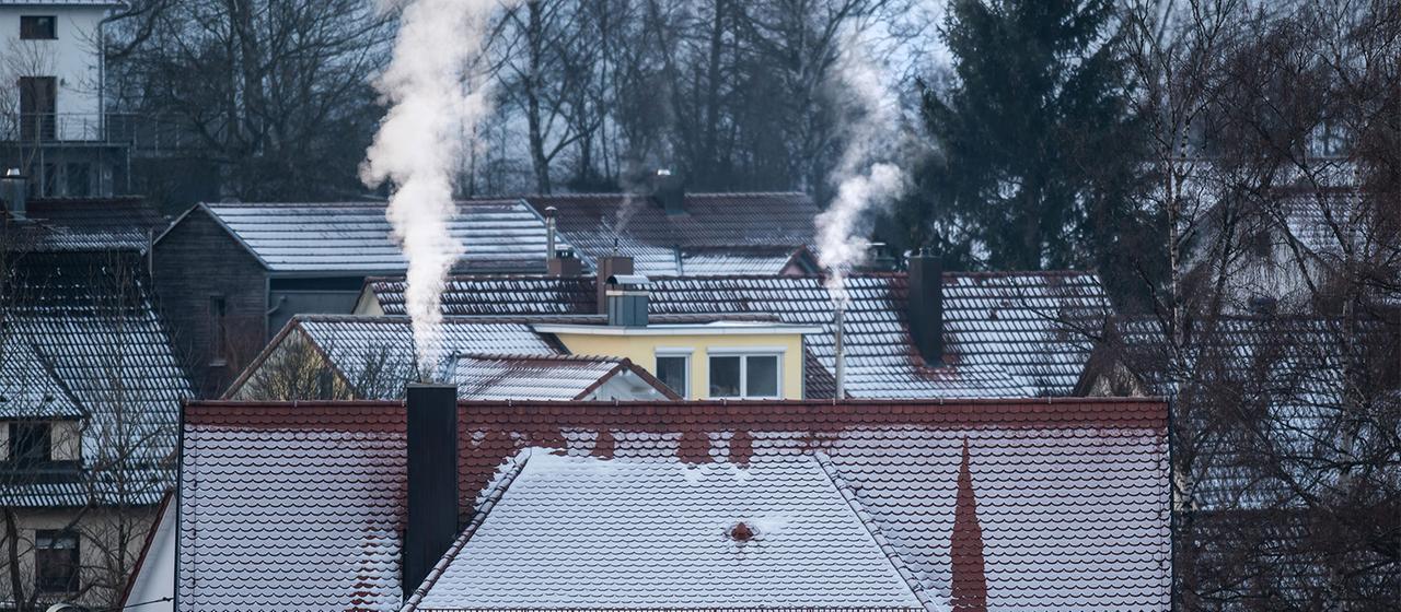 Weißer Dampf steigt aus Schornsteinen eines Wohnhauses auf.