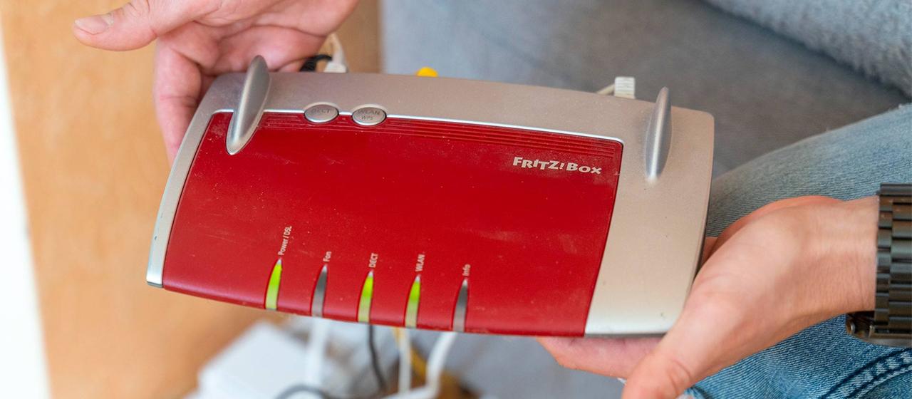 Ein Mann hält einen Fritz Box Router in der Hand