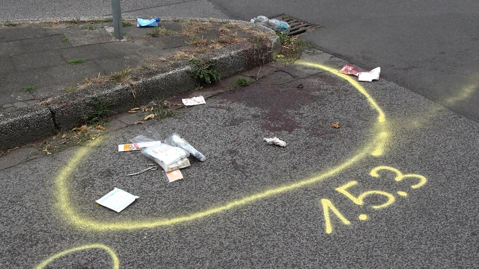 Ein Blutfleck ist auf dem Asphalt zu sehen. Umrandet von einem gelben Kreis aus Kreide.