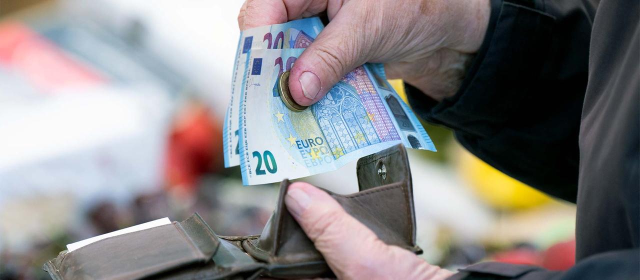 Eine Person mit einem Portemonnaie mit Bargeld.