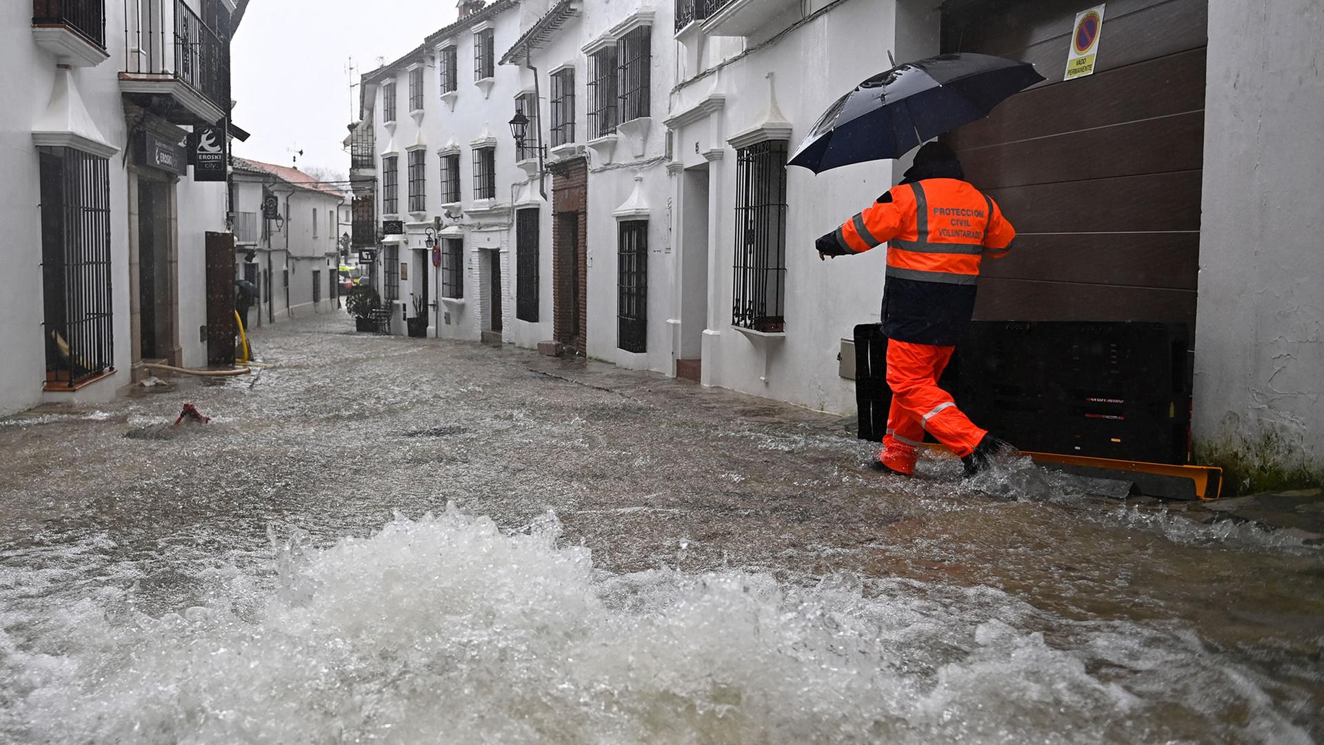 Ein Zivilschutzhelfer geht durch eine überflutete Straße in Grazalema (Spanien). | AFP