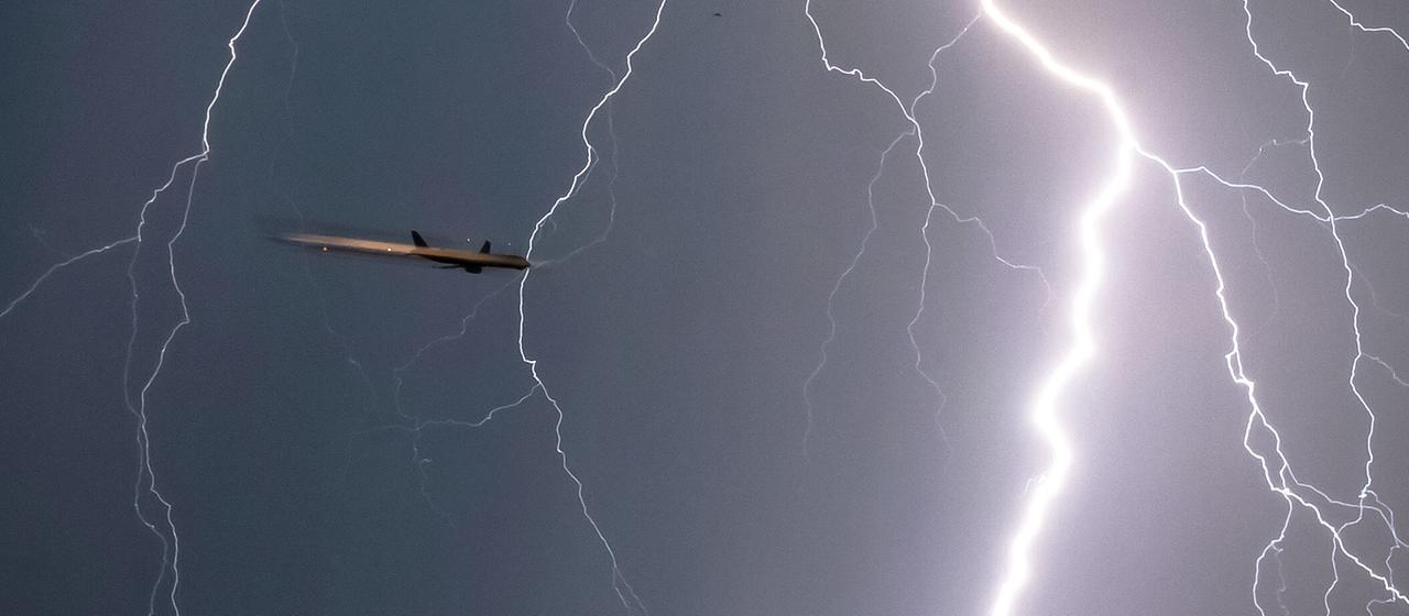 Ein Blitz durchzuckt den Himmel während sich ein Flugzeug im Landeanflug befindet (Archivbild)