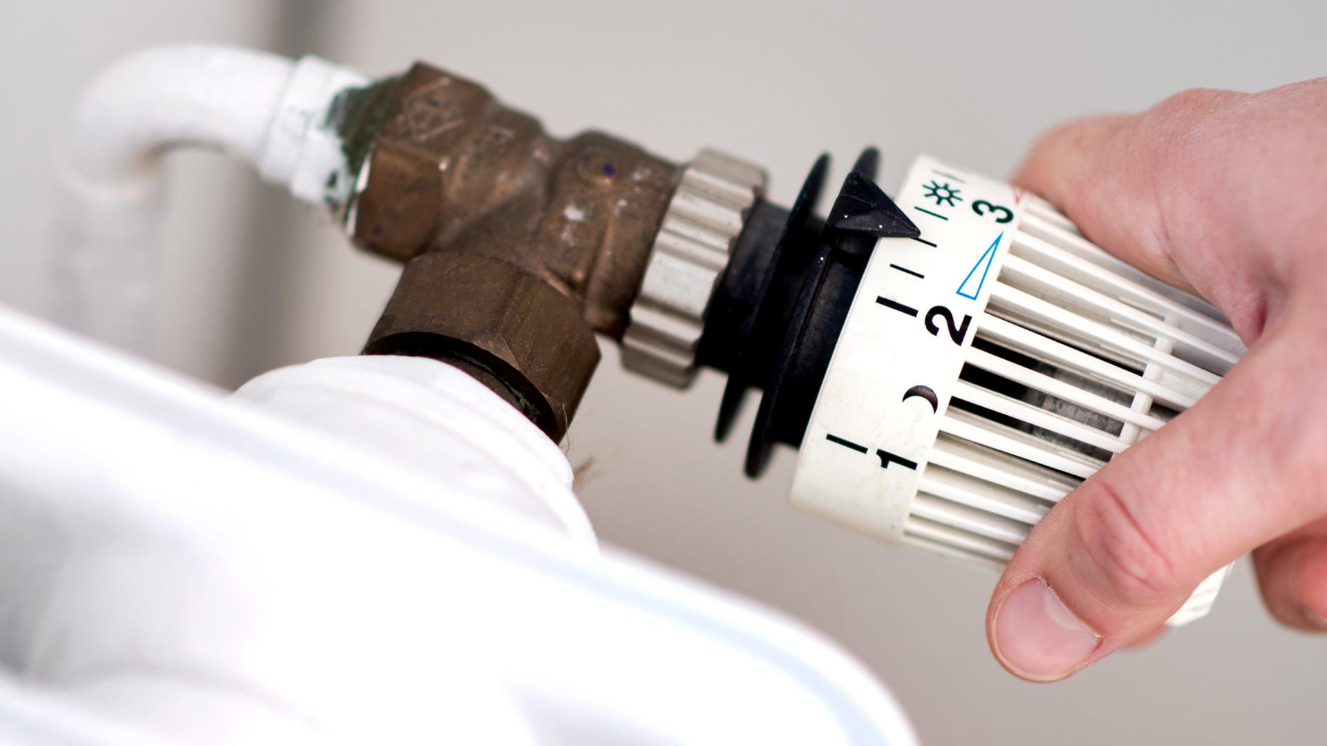 Eine Frau dreht am Thermostat einer Heizung. | dpa