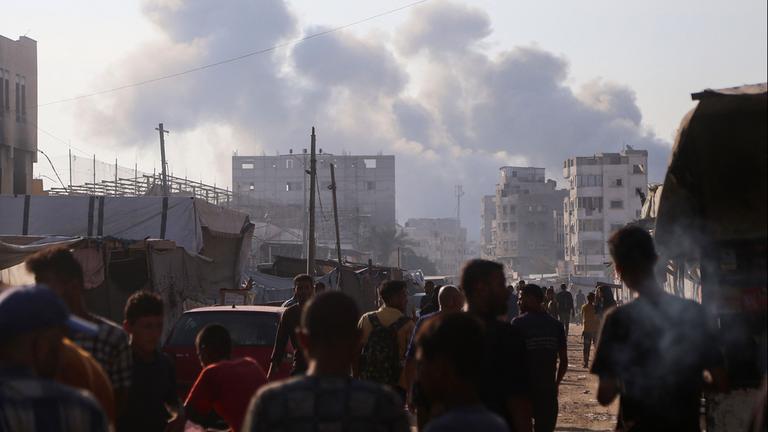 Menschen in Chan Yunis nach israelischen Angriffen vor Rauchschwaden und beschädigten Häusern