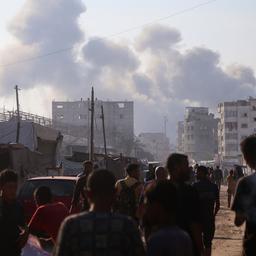 Menschen in Chan Yunis nach israelischen Angriffen vor Rauchschwaden und beschädigten Häusern