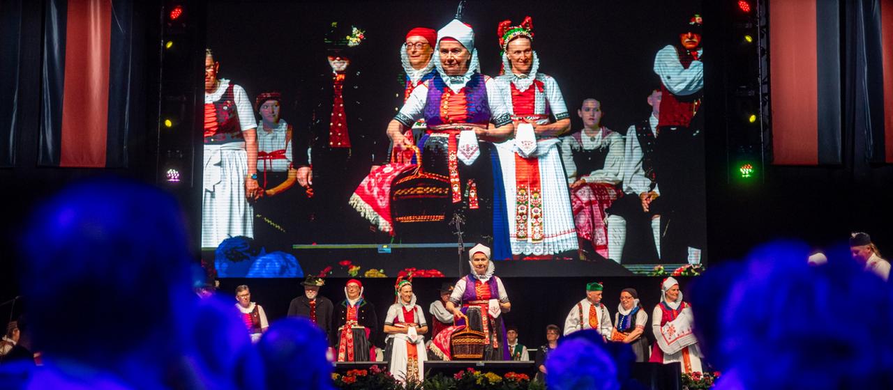 Sudetendeutsche in Tracht stehen auf einer Bühne