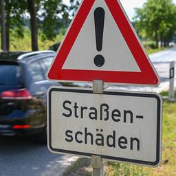 Ein Schild mit der Aufschrift «Straßenschäden» ist an einer Straße zu lesen.