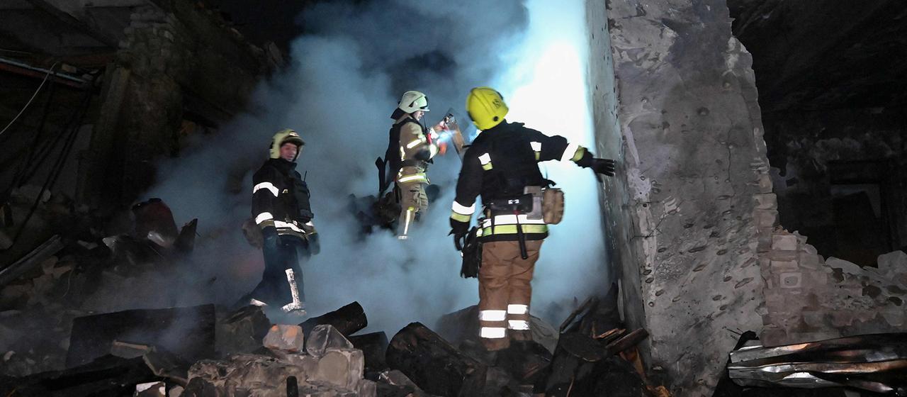 Feuerwehrleute löschen ein brennendes Haus.