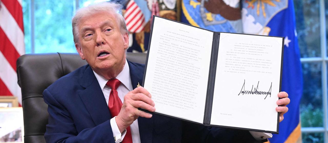 Donald Trump hält im Oval Office eine Präsidentenverfügung. | AFP Donald Trump hält im Oval Office eine Präsidentenverfügung.