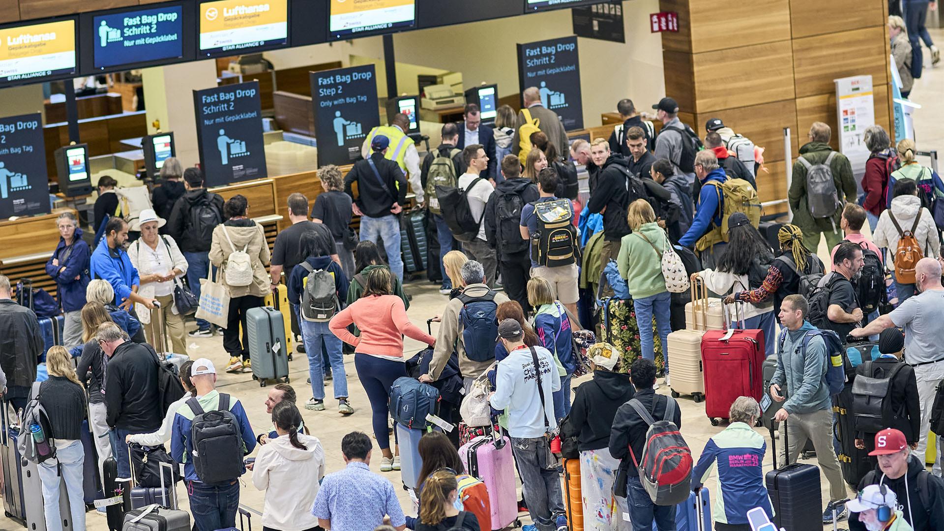 Fluggäste warten vor den Check-in-Schaltern im Terminal 1 des Flughafens Berlin Brandenburg. (22.09.2025) | dpa
