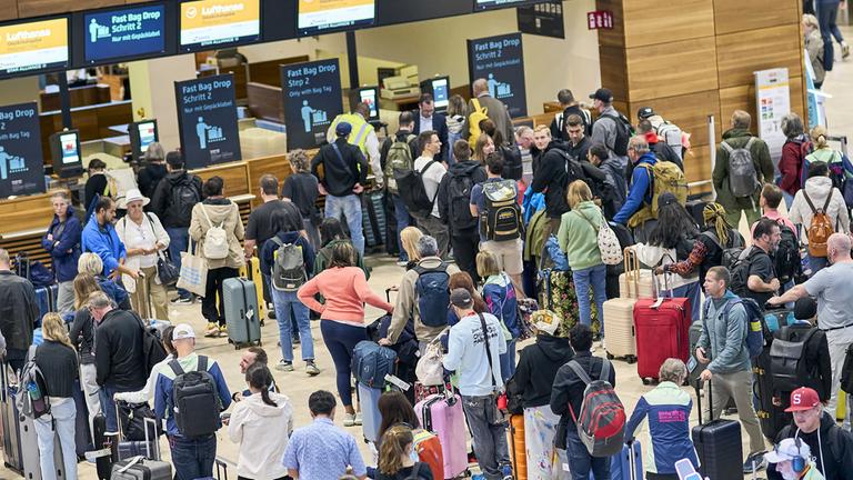 Fluggäste warten vor den Check-in-Schaltern im Terminal 1 des Flughafens Berlin Brandenburg. (22.09.2025)