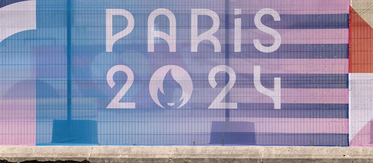 Das Logo der Olympischen Spiele in Paris hängt an einem Zaun.