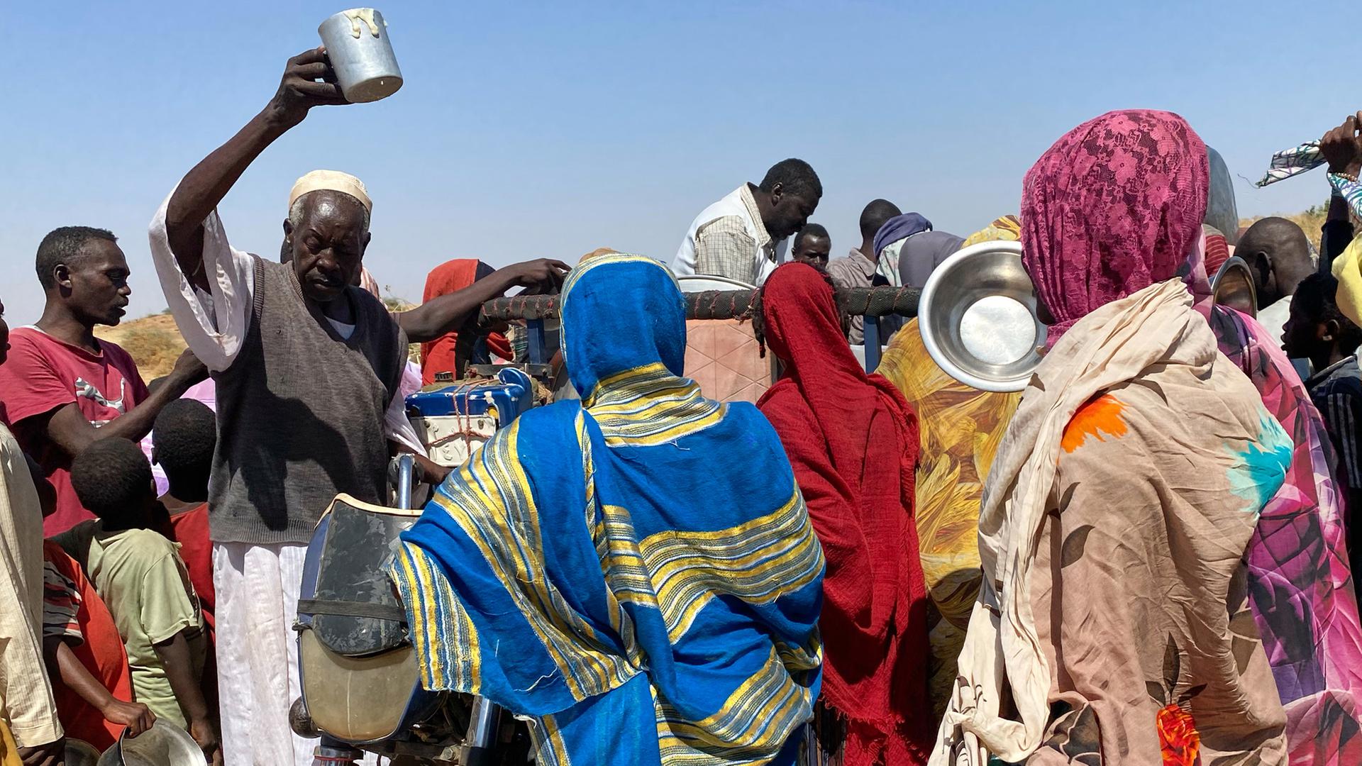 Menschen stehen in einem Flüchtlingslager in Tawila (Sudan) für Nahrungsmittel an. | dpa