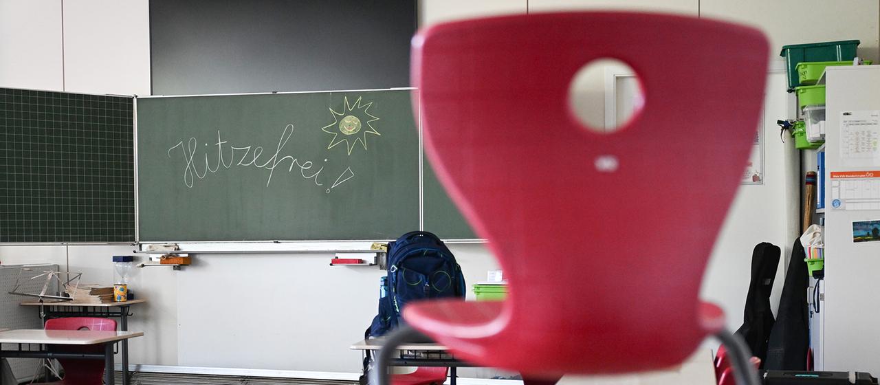 In einem Klassenzimmer steht an der Tafel "Hitzefrei!".